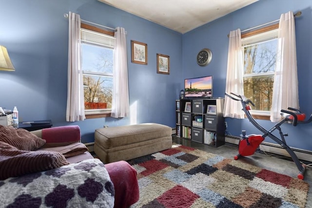 living area featuring a baseboard heating unit, plenty of natural light, and concrete flooring