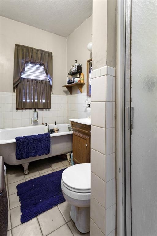 bathroom with tile patterned flooring, vanity, tile walls, a bathtub, and toilet