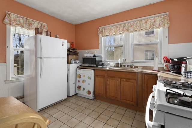 kitchen featuring sink, white appliances, washer / clothes dryer, and light tile patterned flooring