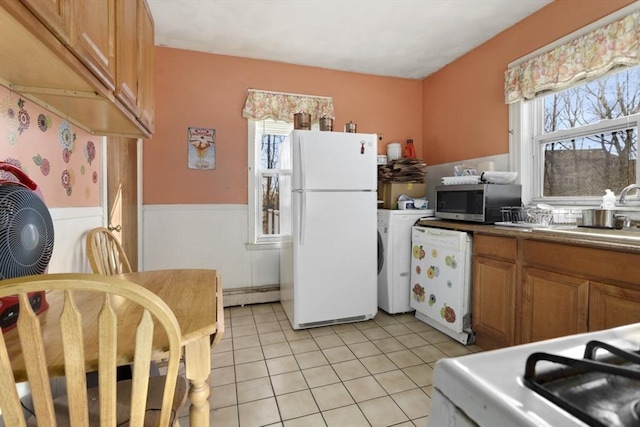 kitchen featuring sink, white appliances, light tile patterned floors, and a wealth of natural light