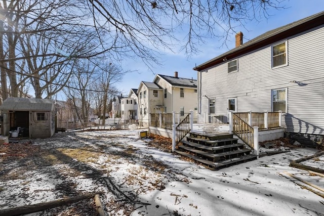 snow covered house featuring a storage unit and a deck