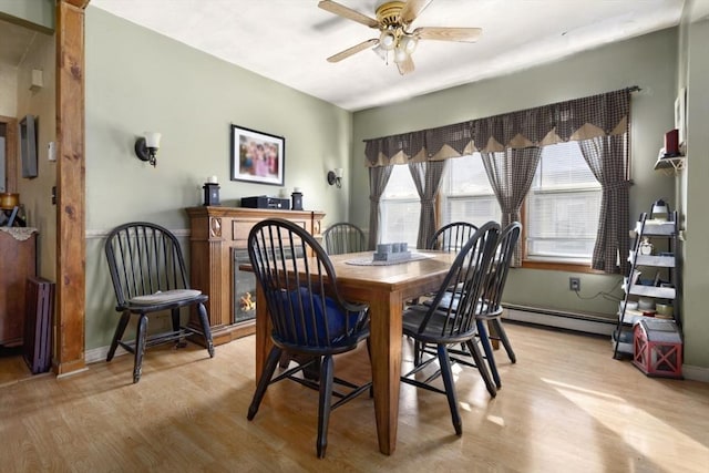 dining room featuring ceiling fan, a baseboard heating unit, and light wood-type flooring