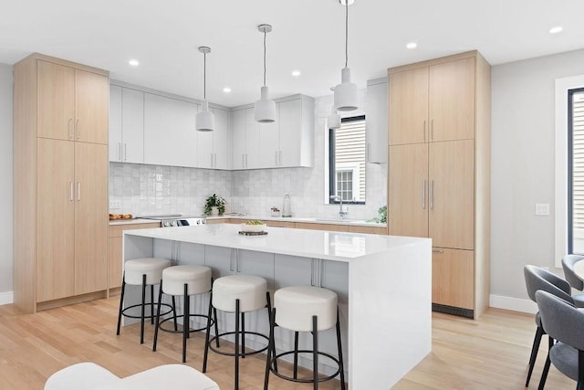 354 Linwood Ave Unit 354, Newton, MA 02460 - kitchen with a kitchen bar, light wood-style flooring, a kitchen island, decorative backsplash, and recessed lighting