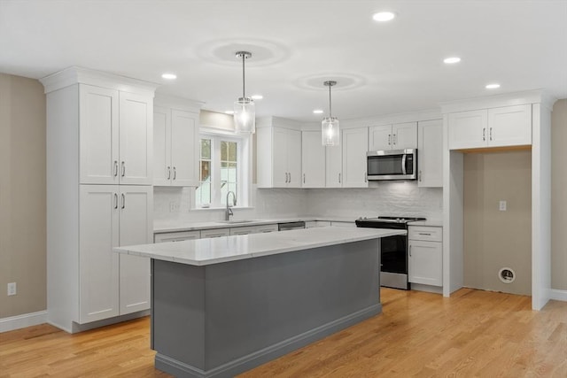 kitchen featuring stainless steel appliances, white cabinetry, a kitchen island, and pendant lighting