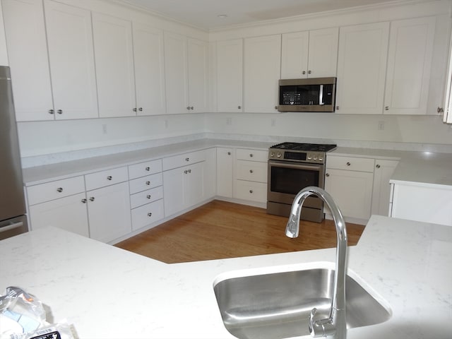 kitchen featuring light stone counters, white cabinetry, appliances with stainless steel finishes, sink, and light hardwood / wood-style floors