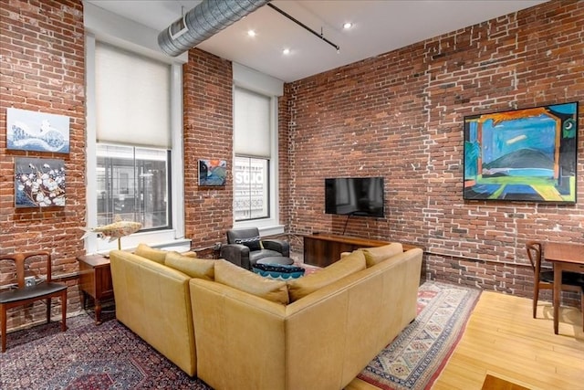 living area featuring brick wall and wood finished floors