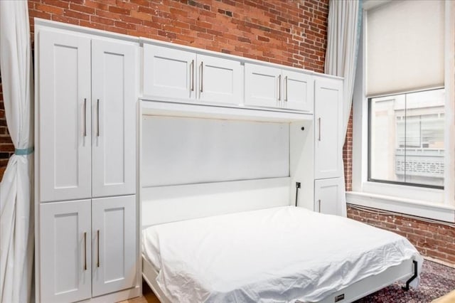 bedroom featuring a wainscoted wall and brick wall