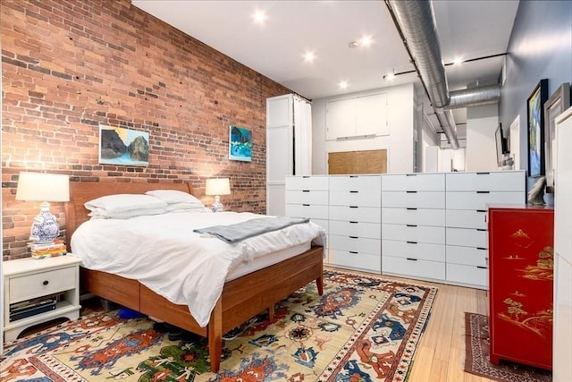 bedroom with brick wall and wood finished floors