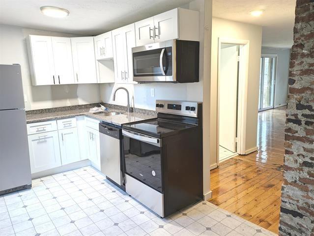 3 S Shore Rd, Salem, NH 03079 - kitchen with stainless steel appliances, white cabinets, dark stone counters, and light wood-style flooring