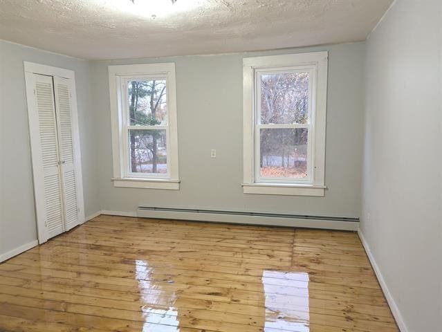 3 S Shore Rd, Salem, NH 03079 - unfurnished bedroom featuring a baseboard radiator, wood-type flooring, a closet, and a textured ceiling