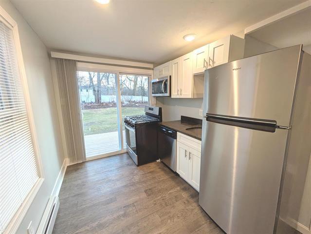 3 S Shore Rd, Salem, NH 03079 - kitchen featuring appliances with stainless steel finishes, dark countertops, wood finished floors, white cabinets, and a baseboard heating unit