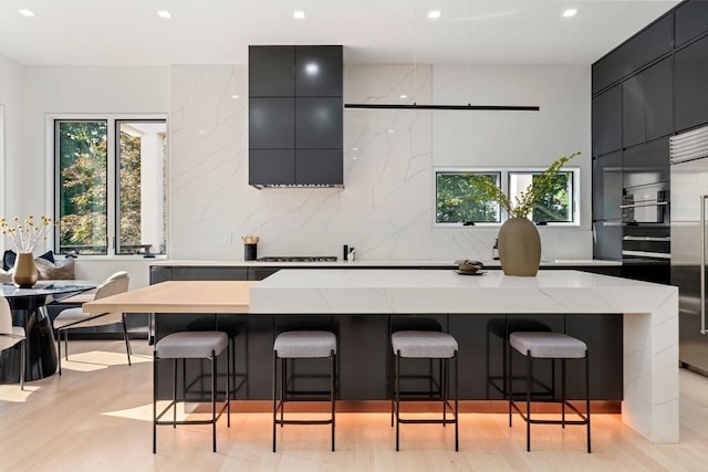 kitchen with a spacious island, a breakfast bar, light hardwood / wood-style floors, and backsplash