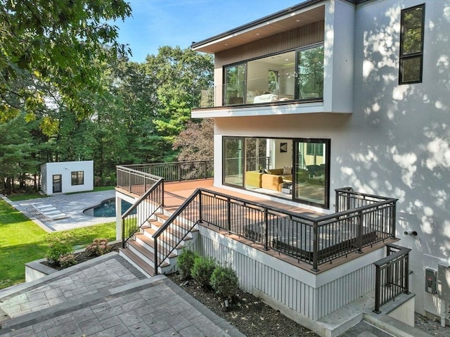 rear view of property featuring a swimming pool, an outbuilding, and a patio area