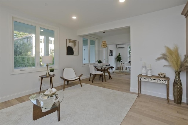 living area with a wall mounted AC and light hardwood / wood-style floors