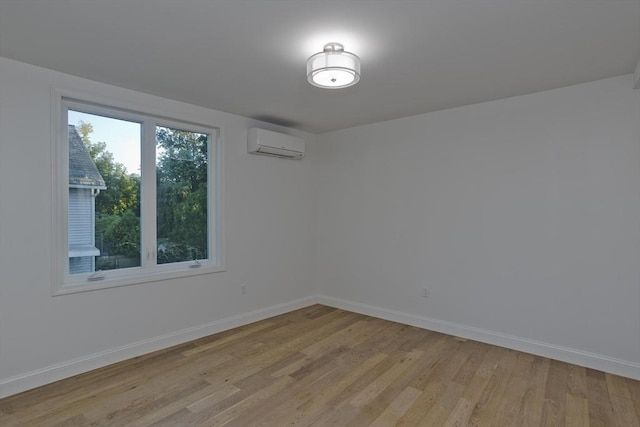 spare room with a wall mounted air conditioner and light hardwood / wood-style floors