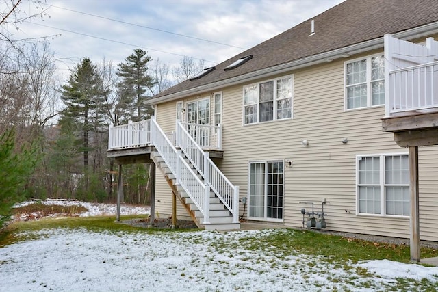 snow covered rear of property with a deck