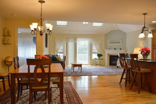 dining room with light hardwood / wood-style flooring, a chandelier, and vaulted ceiling