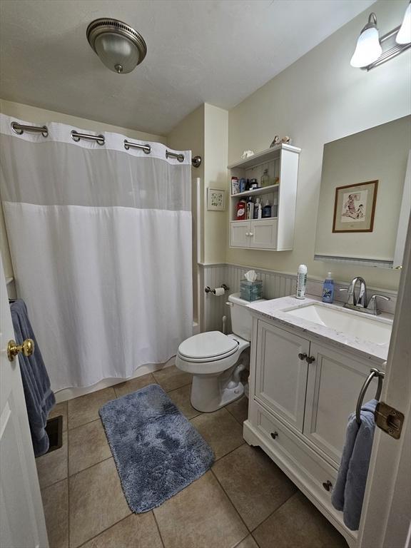 bathroom featuring tile patterned flooring, vanity, a shower with curtain, and toilet