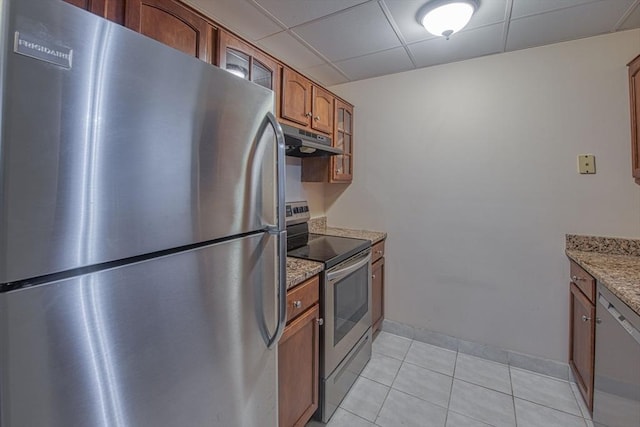 kitchen with stainless steel appliances, light tile patterned flooring, a paneled ceiling, and light stone counters