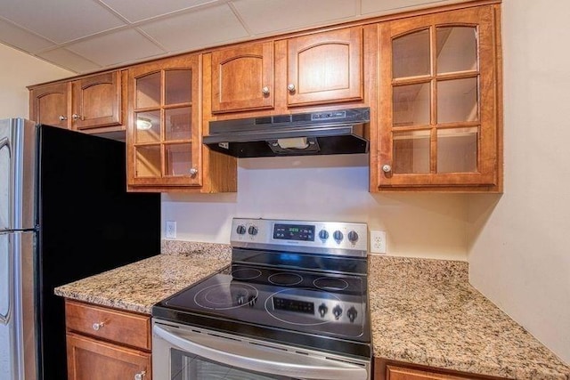 kitchen with stainless steel appliances, light stone countertops, and a paneled ceiling