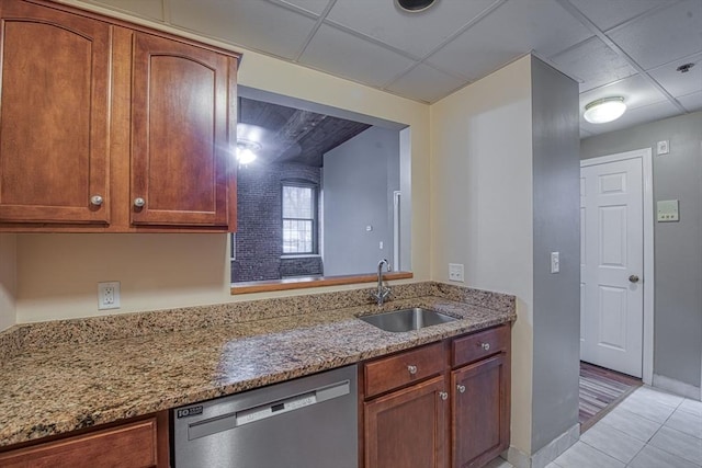 kitchen featuring dishwasher, light stone countertops, sink, and a drop ceiling