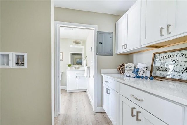 1009 Point Rd, Marion, MA 02738 - washroom with electric panel, light wood-style flooring, cabinet space, and baseboards