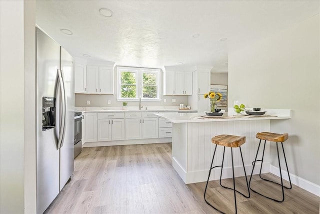 1009 Point Rd, Marion, MA 02738 - kitchen featuring stainless steel fridge, a kitchen bar, light wood-type flooring, range, and a sink