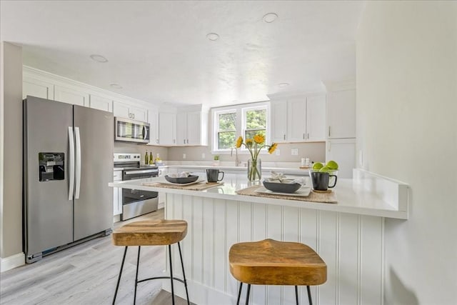 1009 Point Rd, Marion, MA 02738 - kitchen with appliances with stainless steel finishes, white cabinets, light countertops, and a kitchen breakfast bar