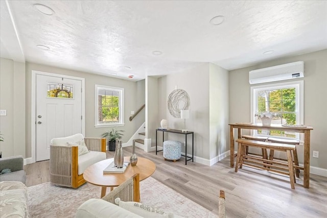 1009 Point Rd, Marion, MA 02738 - living area with an AC wall unit, stairs, baseboards, wood finished floors, and a textured ceiling