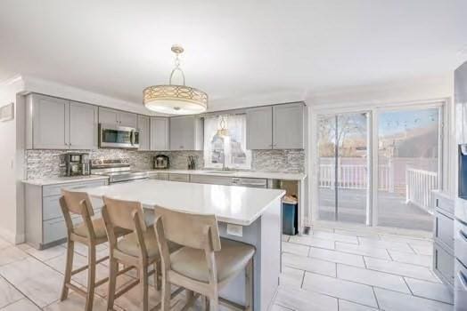 kitchen featuring gray cabinetry, decorative light fixtures, a kitchen island, and range