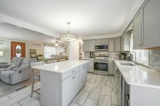 kitchen featuring stainless steel appliances, a center island, sink, and hanging light fixtures