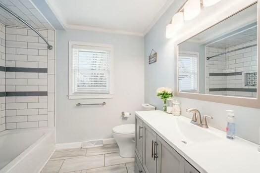 full bathroom with ornamental molding, toilet, vanity, and tiled shower / bath