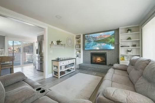 living room with a brick fireplace, light hardwood / wood-style floors, and built in shelves