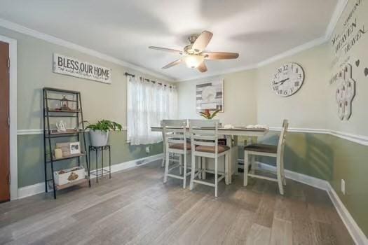 dining space with hardwood / wood-style flooring, crown molding, and ceiling fan