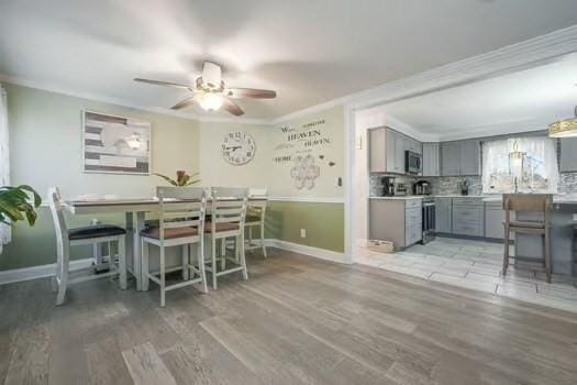 dining space with crown molding, ceiling fan, and light wood-type flooring