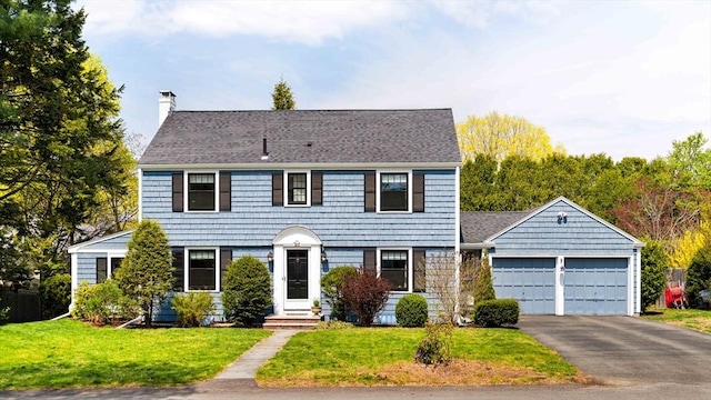 colonial home featuring a front yard, a garage, a chimney, and driveway