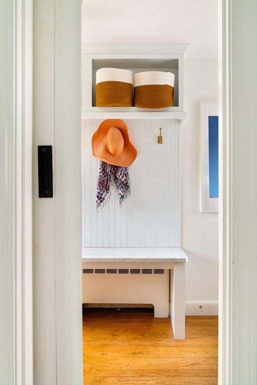 mudroom featuring baseboards, radiator, and wood finished floors