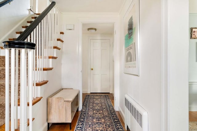 hall featuring baseboards, stairs, radiator heating unit, and wood finished floors