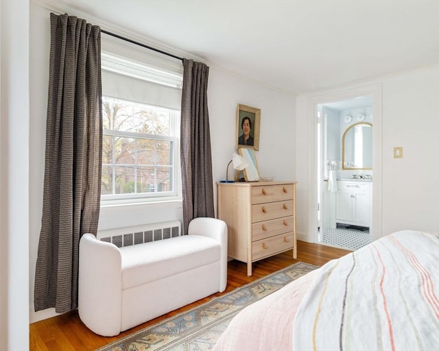 bedroom featuring ensuite bath, wood finished floors, and radiator heating unit