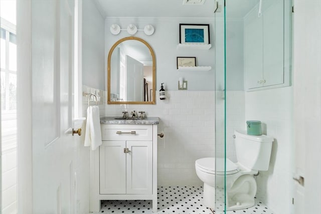 bathroom featuring tile walls, toilet, a wainscoted wall, vanity, and ornamental molding