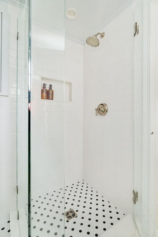full bath featuring crown molding and a shower stall