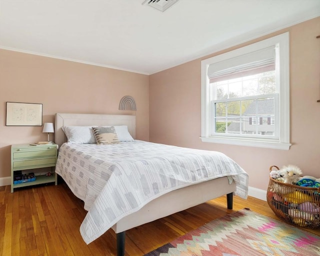 bedroom featuring crown molding, visible vents, wood finished floors, and baseboards