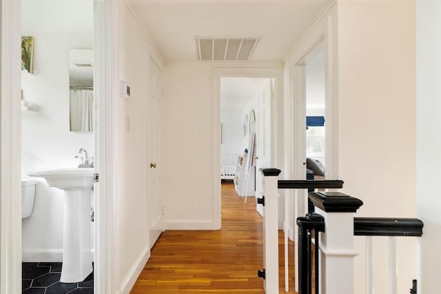hall featuring baseboards, an upstairs landing, visible vents, and wood finished floors