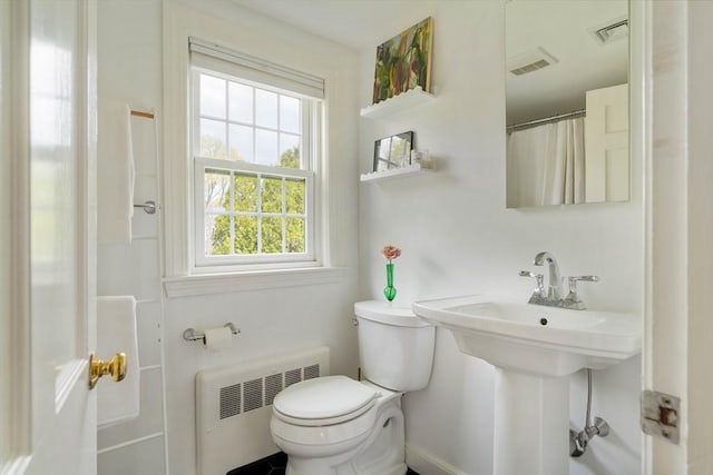 bathroom with toilet, radiator heating unit, and visible vents