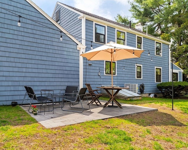 rear view of property featuring a yard, a patio, and a chimney
