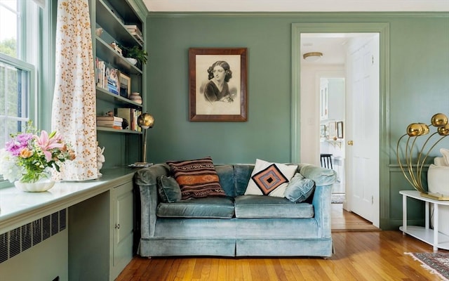 living area with radiator, crown molding, and hardwood / wood-style flooring
