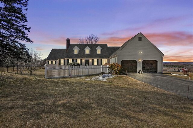 view of front facade featuring a front yard, a chimney, fence private yard, and driveway