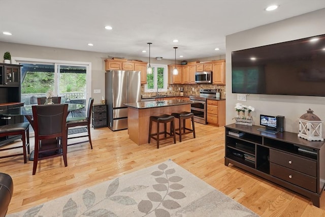 21 Rose Ln, Uxbridge, MA 01569 - kitchen with appliances with stainless steel finishes, a center island, dark countertops, light wood finished floors, and healthy amount of natural light