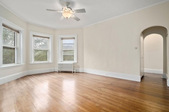 369 Tappan St Unit 8, Brookline, MA 02445 - spare room featuring radiator heating unit, arched walkways, wood finished floors, ceiling fan, and crown molding
