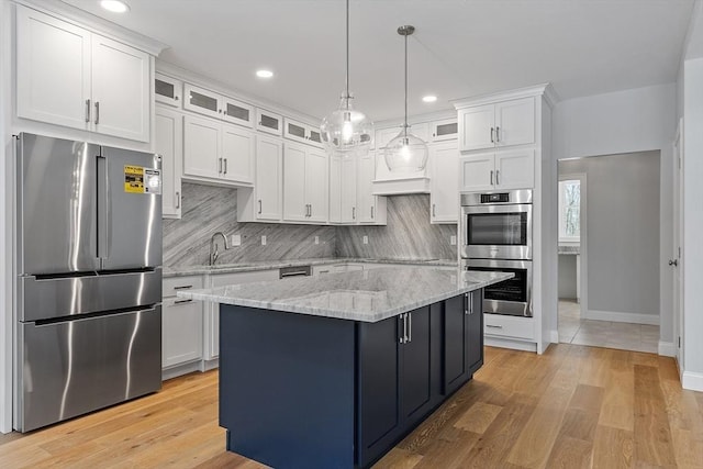 kitchen with hanging light fixtures, appliances with stainless steel finishes, tasteful backsplash, white cabinetry, and a center island